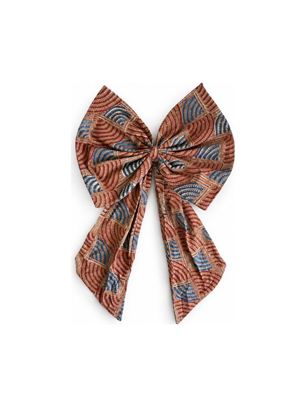 Neela Bow in rust and blue print, top-down on white