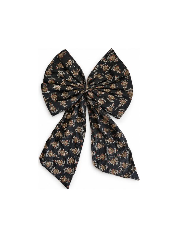 Neela Bow in black with gold flowers, top-down on white